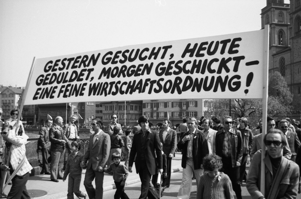 1. Mai-Umzug, "Gestern Gesucht, heute geduldet, morgen geschickt – eine feine Wirtschaftsordnung" Münsterbrücke Zürich, 1976. Quellennachweis: Schweizerisches Sozialarchiv, Sozarch_F_5069-Na-003-018.
