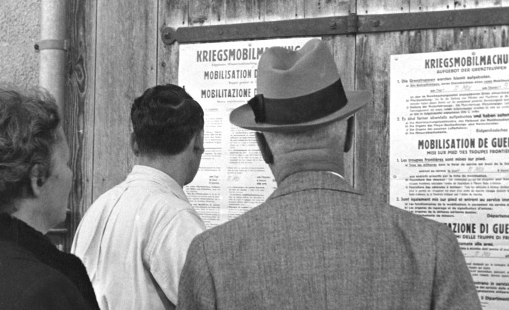 Männer und Frau lesen ein Plakat, das 1939 die Kriegsmobilmachung verkündet, 1939, Fotografie von Hermann Freytag, Schweizerisches Sozialarchiv.